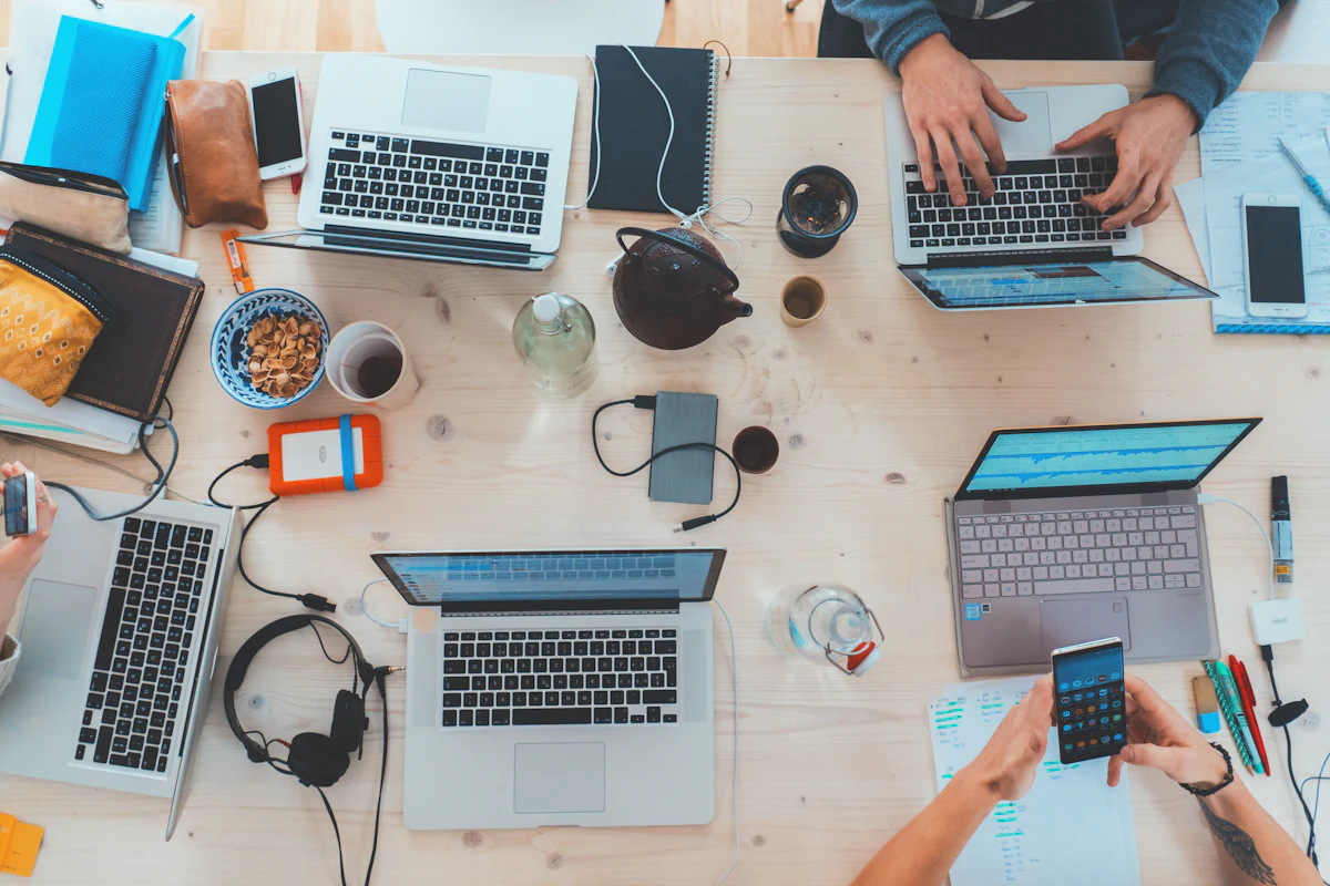 Arbeitstisch von oben mit mehreren Laptops und Händen